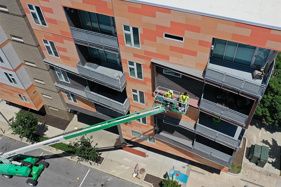 Painters using lift truck to reach all floors of apartment building
